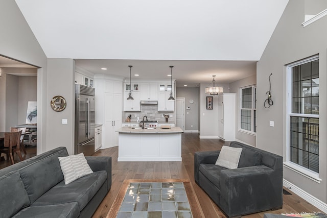 living room with lofted ceiling, dark hardwood / wood-style floors, sink, and a chandelier