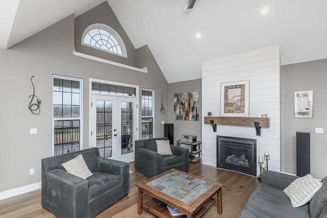 living room with french doors, a large fireplace, wood-type flooring, and high vaulted ceiling