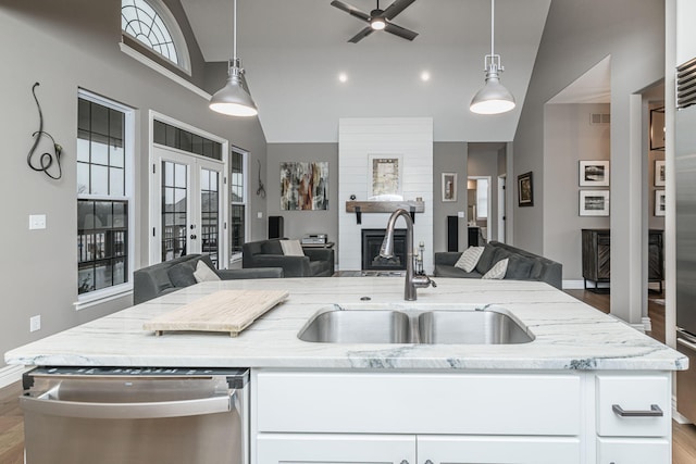 kitchen with pendant lighting, stainless steel dishwasher, light stone countertops, and sink