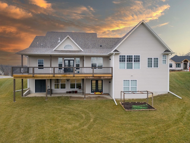 back house at dusk featuring a patio, a lawn, french doors, and a wooden deck