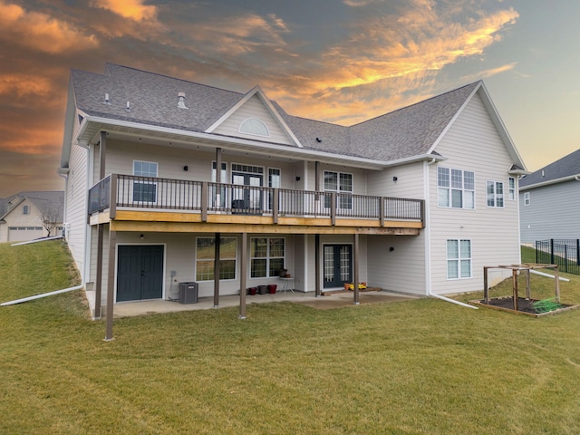 back house at dusk with cooling unit, a wooden deck, a patio area, and a lawn