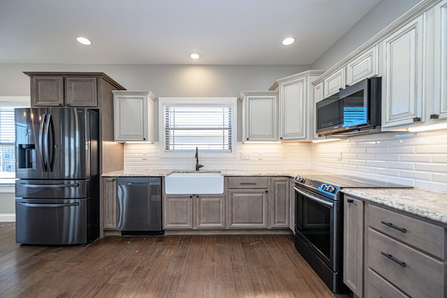 kitchen with light stone counters, sink, dark hardwood / wood-style floors, and appliances with stainless steel finishes