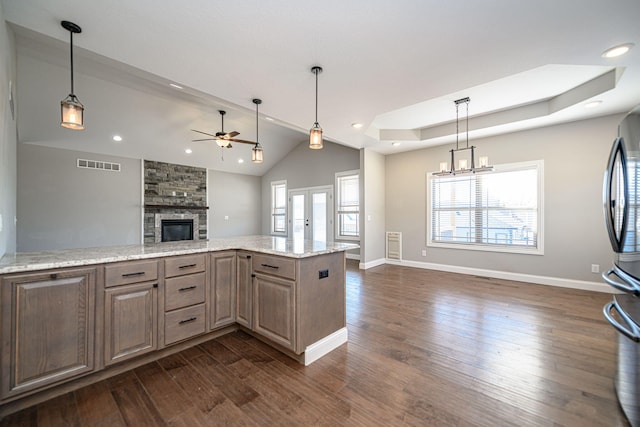 kitchen featuring dark hardwood / wood-style floors, a fireplace, stainless steel fridge, and light stone countertops