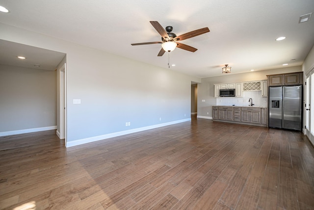 unfurnished living room featuring ceiling fan, sink, and dark hardwood / wood-style flooring