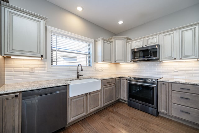 kitchen with sink, light stone counters, dark hardwood / wood-style floors, stainless steel appliances, and backsplash