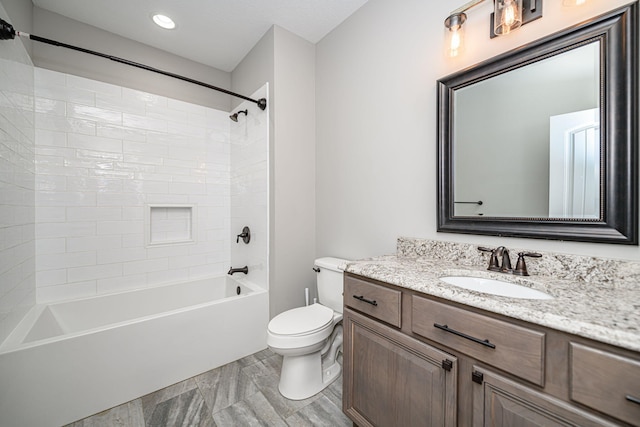 full bathroom featuring vanity, tiled shower / bath, and toilet