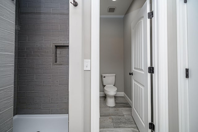 bathroom featuring a tile shower and toilet