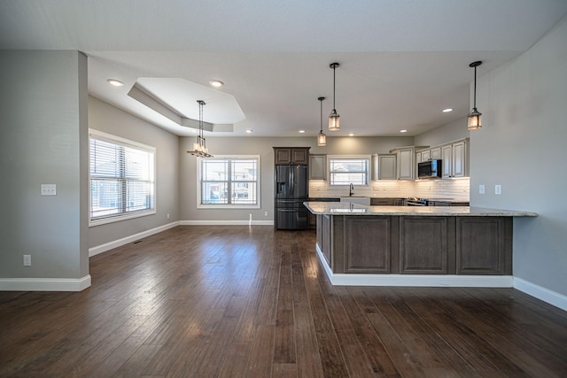 kitchen featuring appliances with stainless steel finishes, sink, decorative backsplash, light stone counters, and a tray ceiling