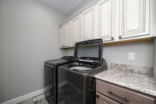 laundry room featuring separate washer and dryer and cabinets