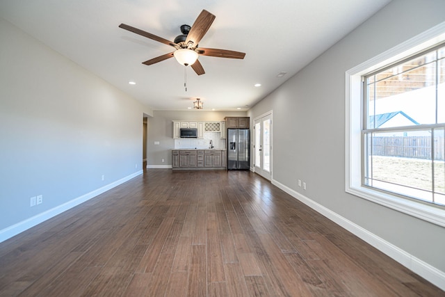 unfurnished living room with plenty of natural light, dark hardwood / wood-style floors, and ceiling fan