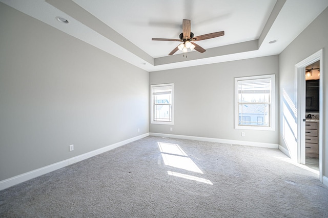 carpeted empty room with a tray ceiling and ceiling fan