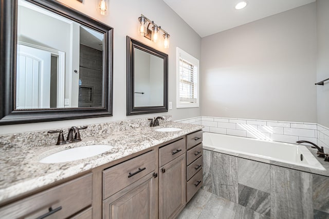 bathroom featuring vanity and tiled tub