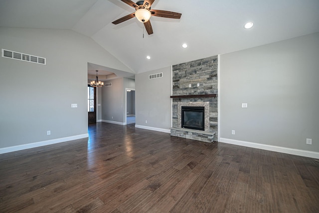 unfurnished living room featuring dark wood-type flooring, lofted ceiling, a stone fireplace, and ceiling fan with notable chandelier