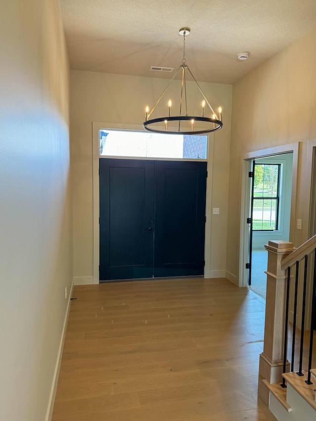 entrance foyer featuring a notable chandelier, light hardwood / wood-style flooring, and a textured ceiling