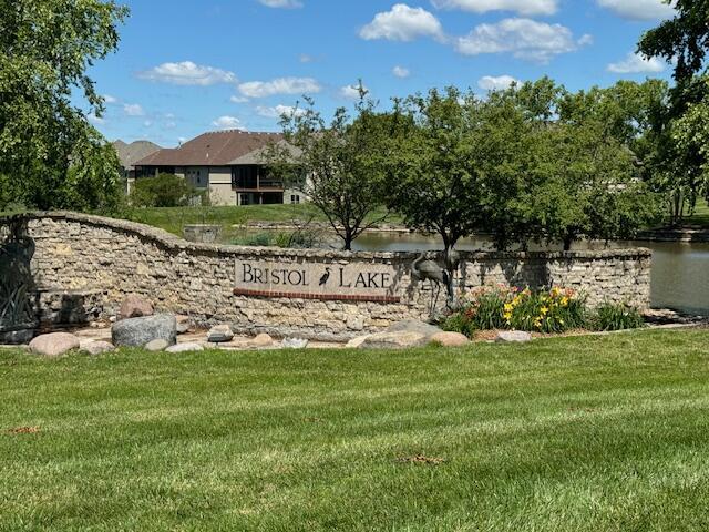 community / neighborhood sign with a lawn and a water view