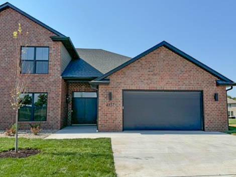 view of front of property featuring concrete driveway, an attached garage, brick siding, and a front yard