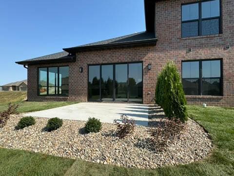 back of property with a patio, a yard, and brick siding