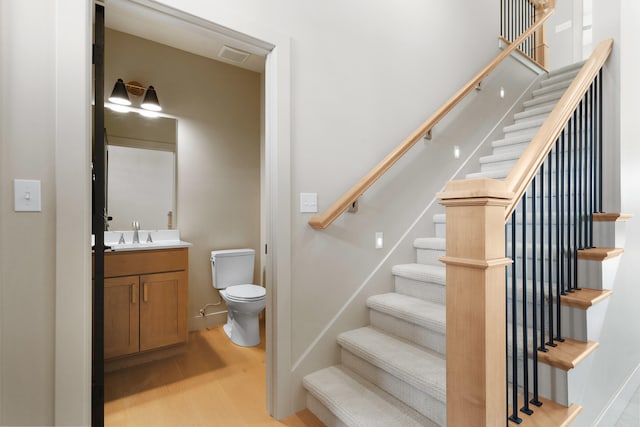 staircase with visible vents, baseboards, and wood finished floors