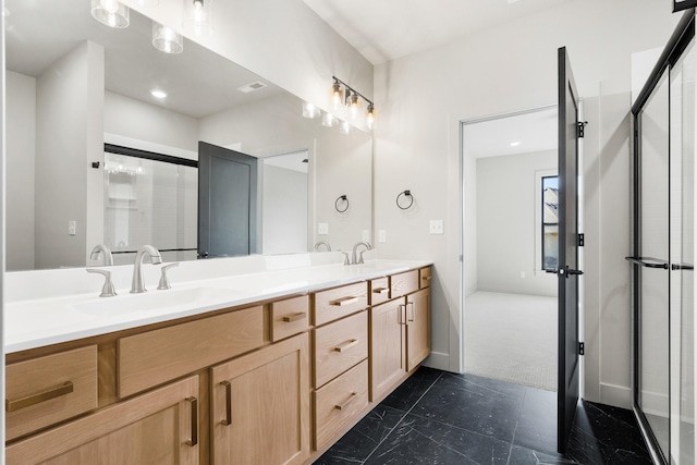 bathroom featuring double vanity, a shower with shower door, and a sink