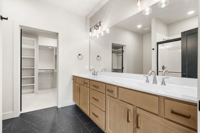 bathroom with a sink, a walk in closet, a shower with shower door, and double vanity