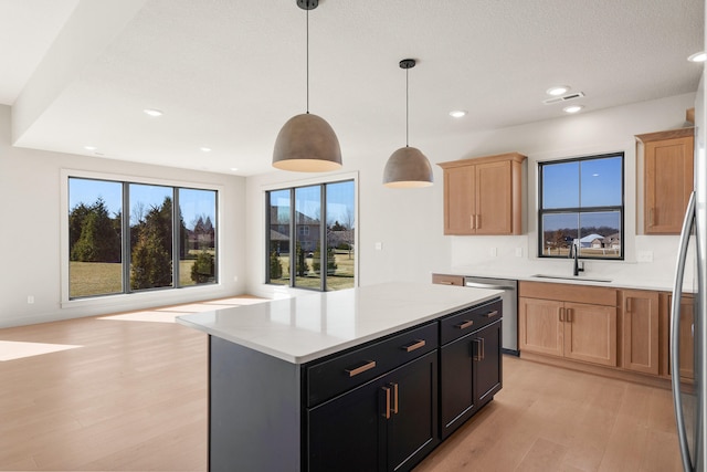 kitchen featuring light brown cabinetry, dishwasher, light countertops, light wood-style flooring, and a sink