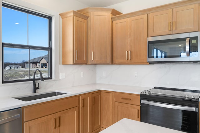 kitchen with tasteful backsplash, light brown cabinets, light countertops, appliances with stainless steel finishes, and a sink