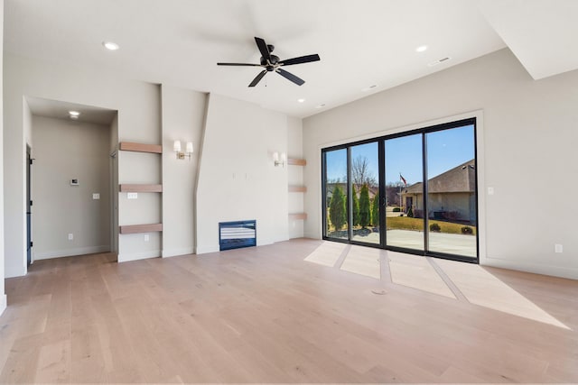 unfurnished living room with a ceiling fan, baseboards, light wood finished floors, recessed lighting, and a glass covered fireplace