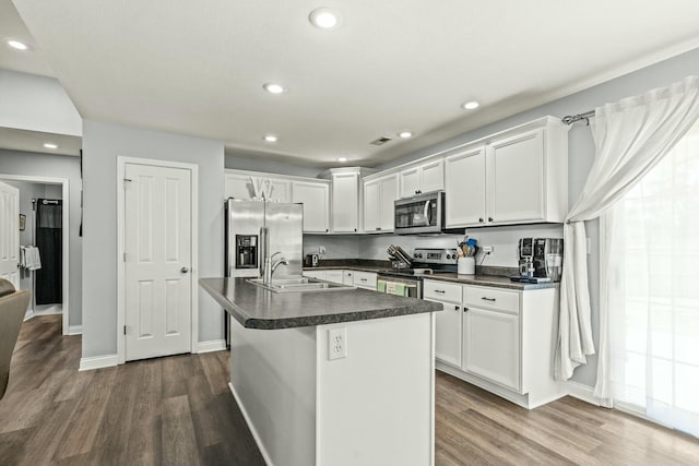 kitchen with appliances with stainless steel finishes, dark hardwood / wood-style floors, white cabinetry, an island with sink, and sink