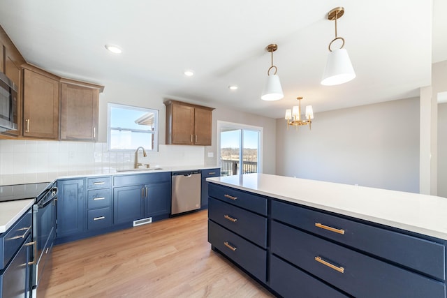 kitchen with sink, appliances with stainless steel finishes, tasteful backsplash, light hardwood / wood-style floors, and decorative light fixtures