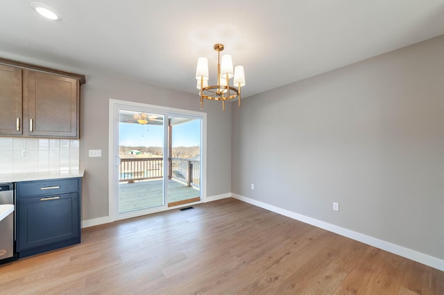 unfurnished dining area with a notable chandelier and light wood-type flooring