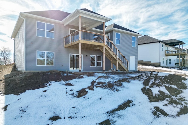 snow covered rear of property with ceiling fan and a balcony