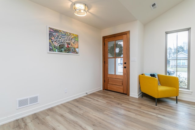 foyer entrance featuring lofted ceiling, a healthy amount of sunlight, and light wood-type flooring