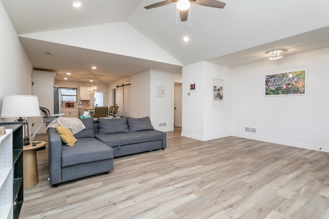 living room featuring high vaulted ceiling, a barn door, ceiling fan, and light wood-type flooring