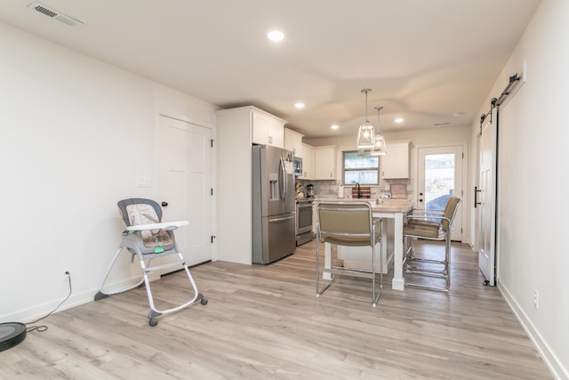 kitchen with a kitchen island, decorative light fixtures, a kitchen bar, stainless steel appliances, and a barn door