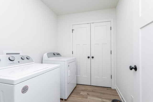 clothes washing area with independent washer and dryer and light wood-type flooring