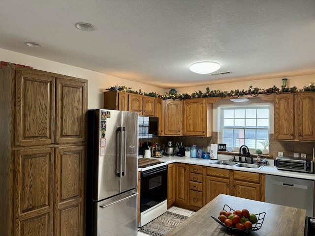 kitchen with appliances with stainless steel finishes, sink, light tile patterned floors, and decorative backsplash