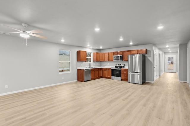 kitchen with stainless steel appliances, sink, ceiling fan, and light hardwood / wood-style flooring