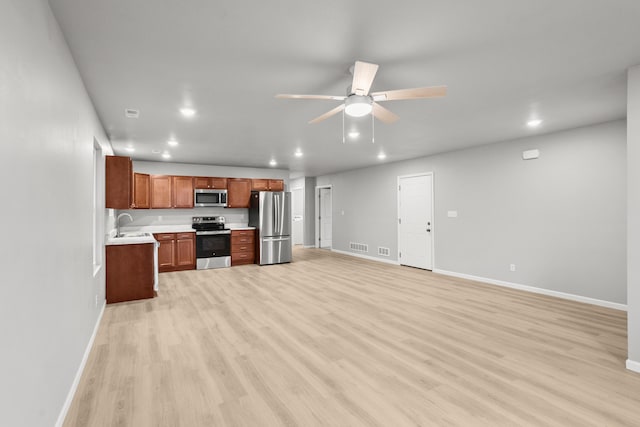 kitchen with ceiling fan, appliances with stainless steel finishes, sink, and light hardwood / wood-style flooring