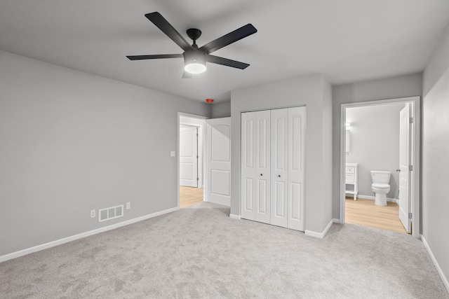 unfurnished bedroom featuring ceiling fan, a closet, ensuite bathroom, and light carpet