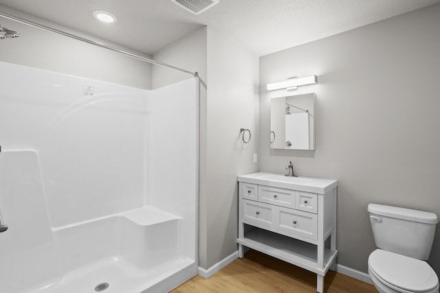 bathroom with wood-type flooring, a shower, vanity, and toilet