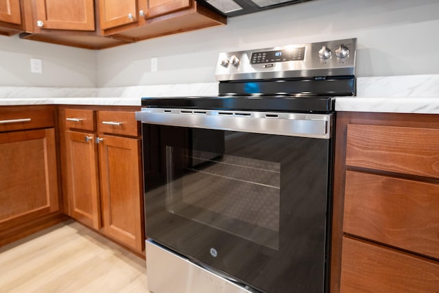 kitchen featuring light stone countertops, stainless steel range with electric cooktop, and light wood-type flooring