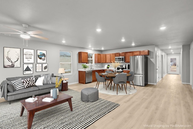 living room featuring sink, light hardwood / wood-style flooring, and ceiling fan