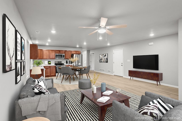 living room with light hardwood / wood-style flooring and ceiling fan