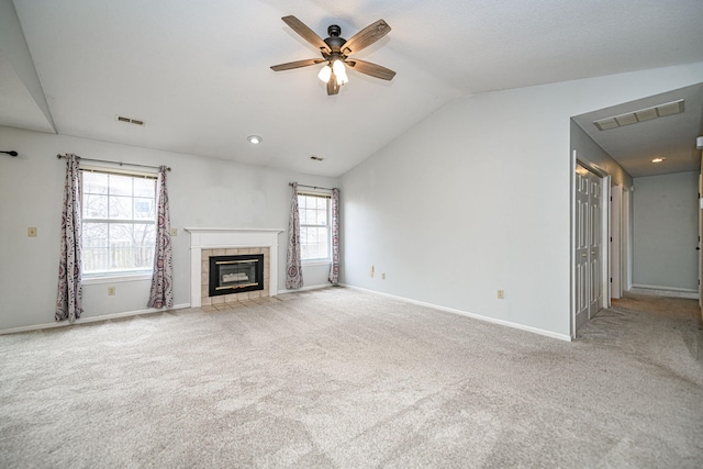 unfurnished living room with ceiling fan, light colored carpet, lofted ceiling, and a tiled fireplace