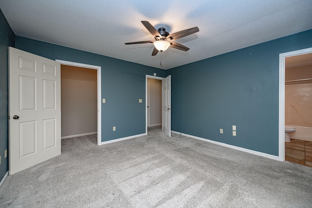 unfurnished bedroom with ceiling fan, light colored carpet, ensuite bath, and a textured ceiling