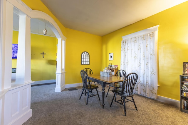 carpeted dining space with ornate columns