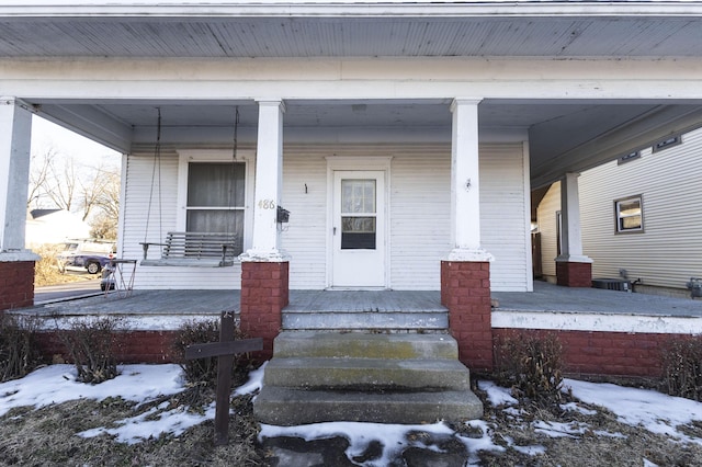 snow covered property entrance with covered porch