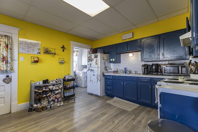 kitchen featuring hardwood / wood-style flooring, white appliances, blue cabinets, and sink