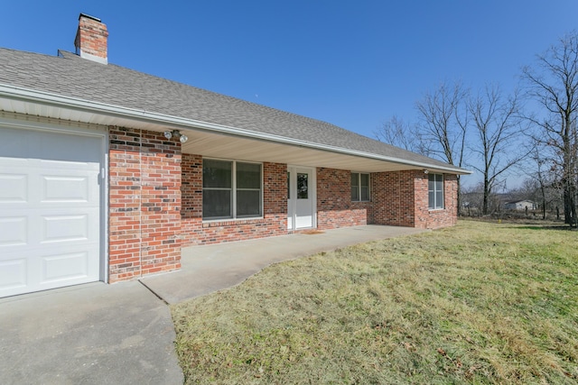 ranch-style home featuring brick siding, an attached garage, a shingled roof, and a front lawn