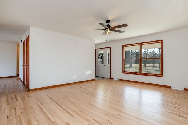 unfurnished room with light wood finished floors, visible vents, a ceiling fan, and baseboards